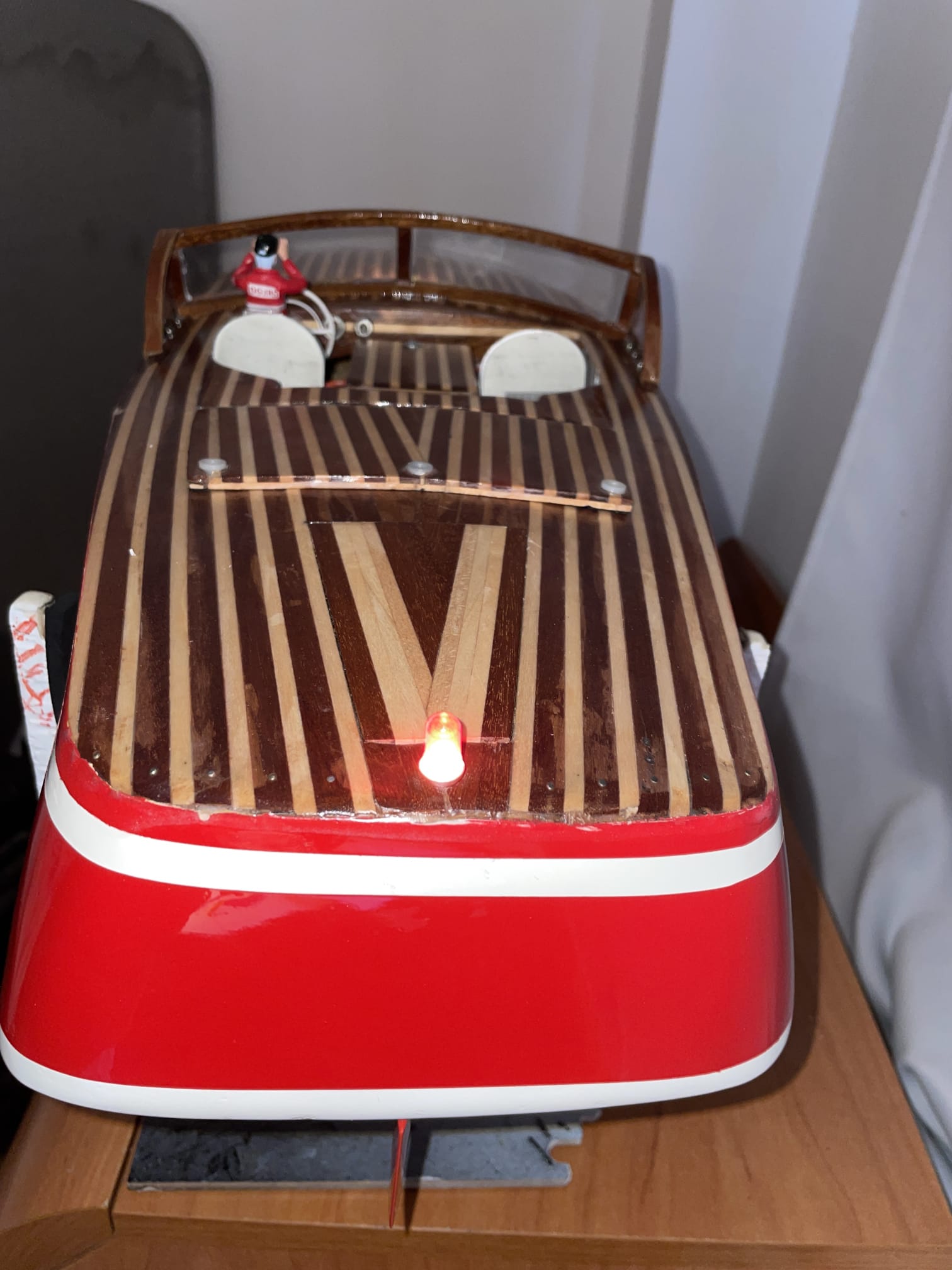 Proa de una lancha clásica con cubierta de tablilla, luz de navegación y detalles cromados