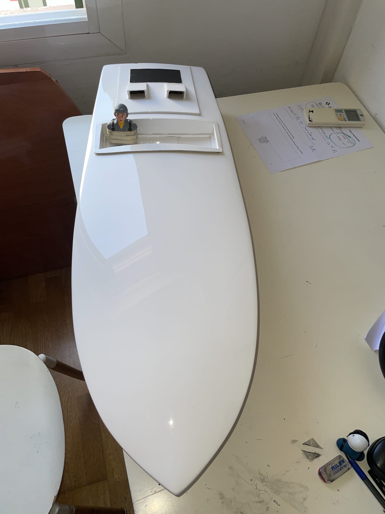 Casco monocasco de competición en blanco brillante con un piloto en miniatura