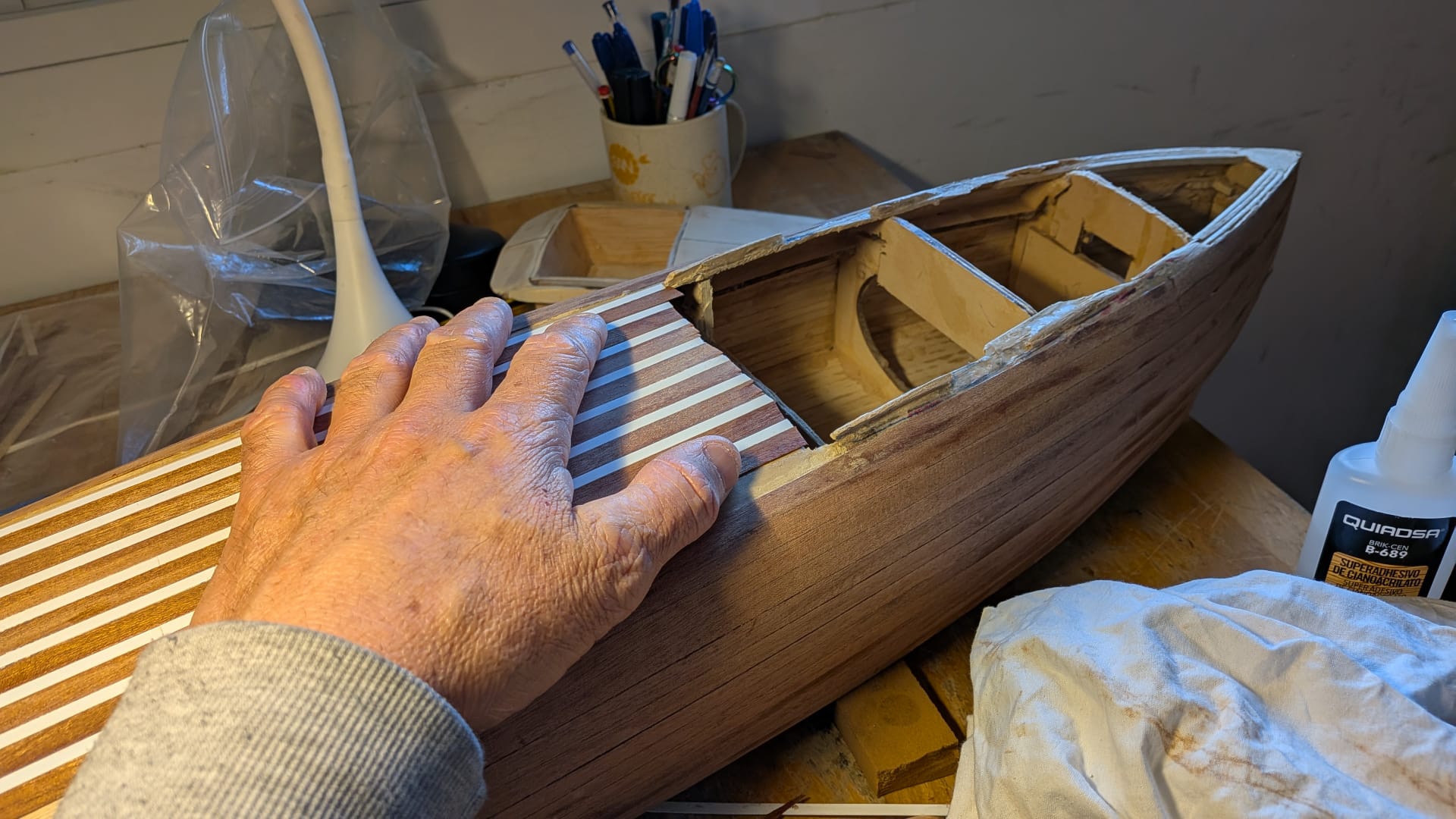 Manos sujetando un casco en el taller junto a un bote de cianoacrilato