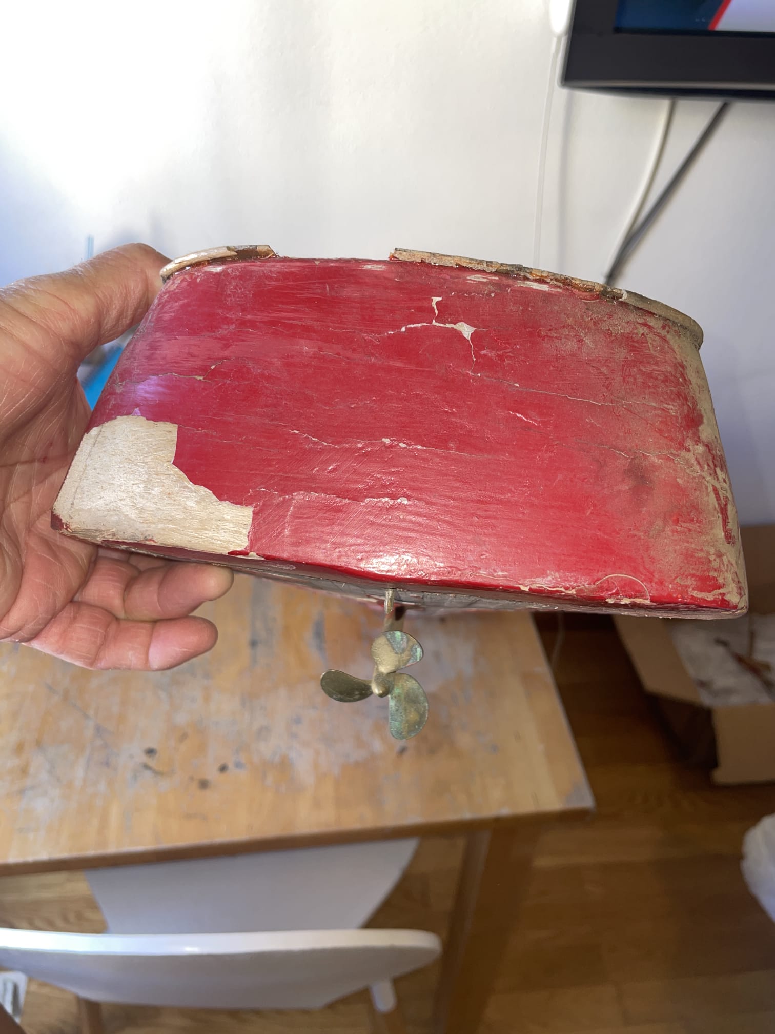 Casco antiguo pintado de rojo con la pintura agrietada, sostenido en la mano