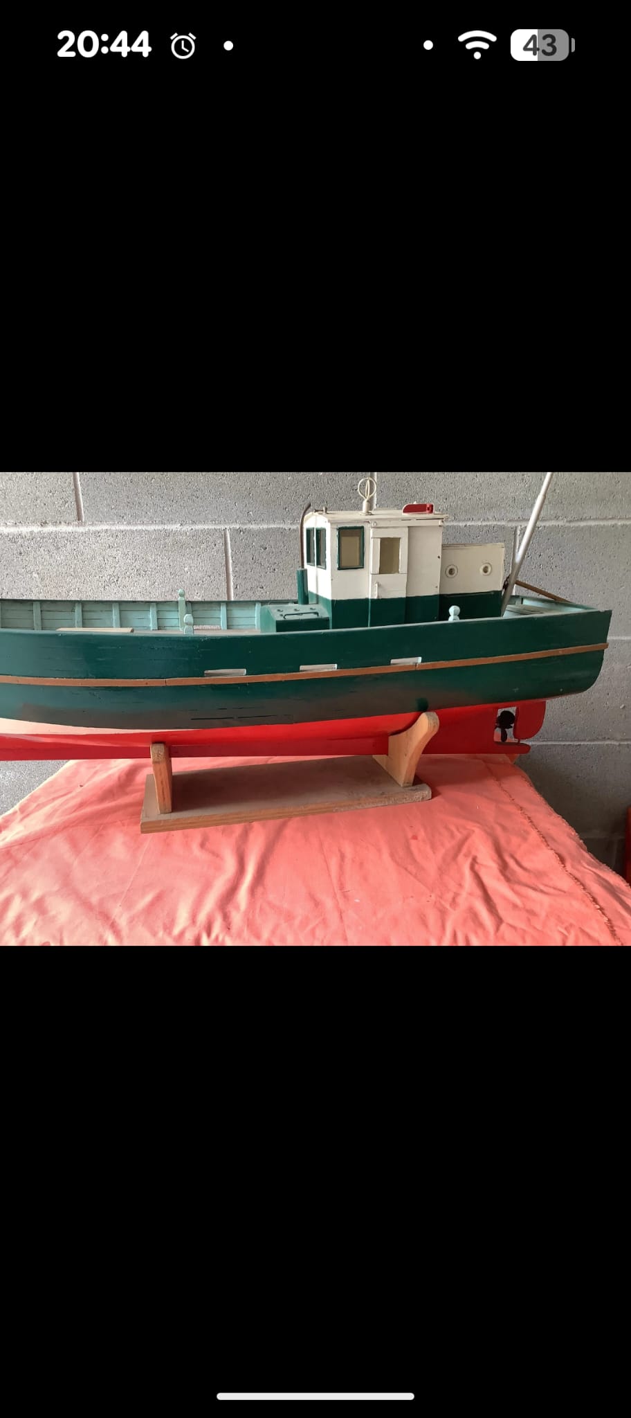 Llaüt mediterráneo de radiocontrol en verde y blanco sobre su peana, en restauración